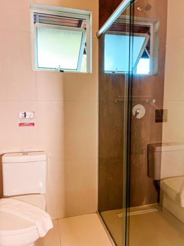 a bathroom with a toilet and a glass shower at Essência do Sol Pousada in Florianópolis