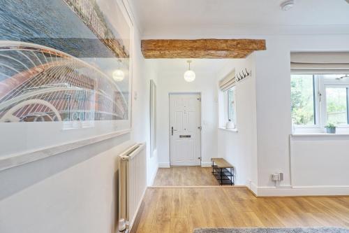 a hallway with white walls and a painting on the wall at Luxury 4-Bed Family Home in Epping with Parking by LMV Property in Epping