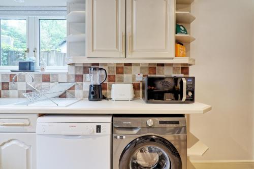 a kitchen with a washing machine and a microwave at Luxury 4-Bed Family Home in Epping with Parking by LMV Property in Epping