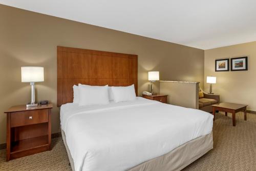 a hotel room with a large bed and a chair at Comfort Inn & Suites East Moline near I-80 in East Moline