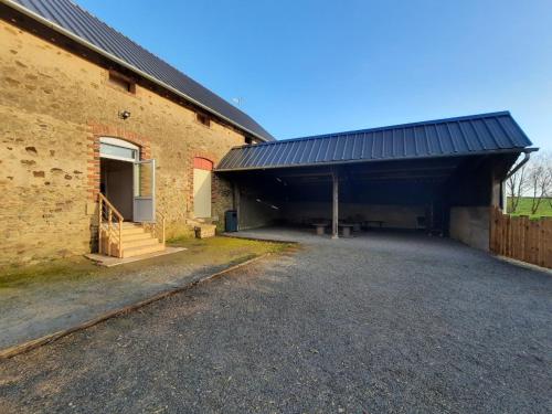 a large brick building with a garage next to it at Gîte de charme à la campagne in Ampoigné