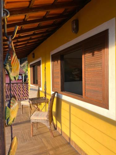 a porch of a house with chairs and a window at Casa amarela in Cambaquara
