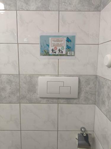 a white tiled bathroom with a sign on the wall at Light Blue Room in Scordia