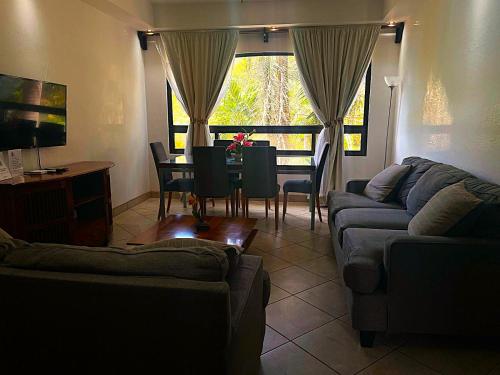 a living room with a couch and a table with chairs at The Oaks Tamarindo Pool Front Condominiums fast wifi in Tamarindo