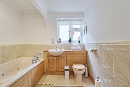 a bathroom with a tub and a toilet and a sink at Luxury 4-Bed Family Home in Epping with Parking by LMV Property in Epping