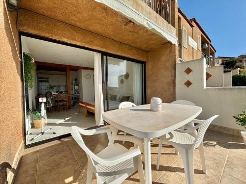 une table blanche et des chaises sur une terrasse dans l'établissement Appartement Vue Mer en Rez-de-Jardin, à Lumio