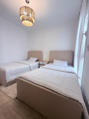 a bedroom with two beds and a chandelier at Comfy Hotel Apartament in Madinaty