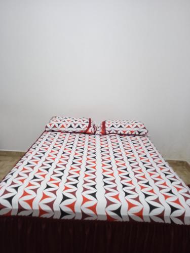 a bed with a red and white comforter at EBORA Afro Cultural in Ilhéus