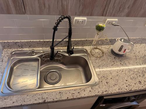 a kitchen sink with a kitchen utensil hanging over it at Comfy Hotel Apartament in Madinaty