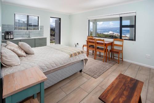 a bedroom with a bed and a table and chairs at Thalassa in Bettyʼs Bay