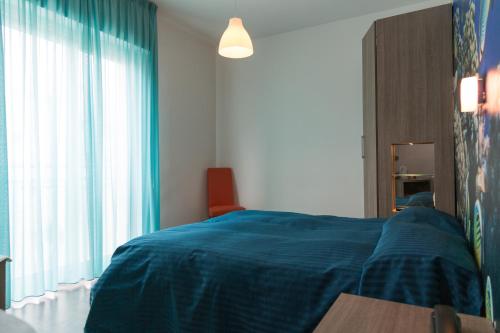 a bedroom with a blue bed and a window at Hotel Miramare in Pineto