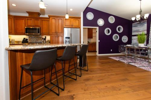 a kitchen with wooden cabinets and a bar with stools at Amethyst Hearth - Family Spa Serenity, Zoo, Beach, Disneyland, Legoland in Vista