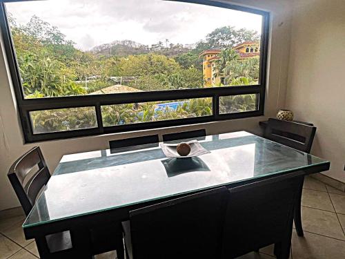 a dining room with a table and a large window at The Oaks Tamarindo Pool Front Condominiums fast wifi in Tamarindo