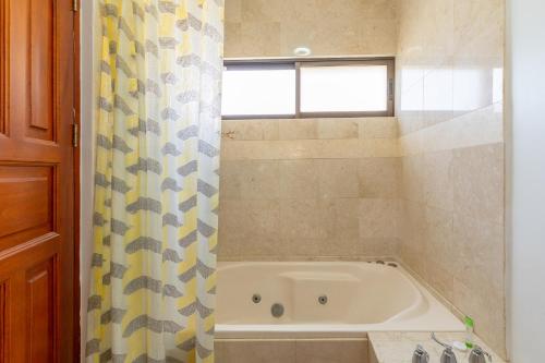 a bath tub in a bathroom with a shower curtain at The Oaks Tamarindo Pool Front Condominiums fast wifi in Tamarindo