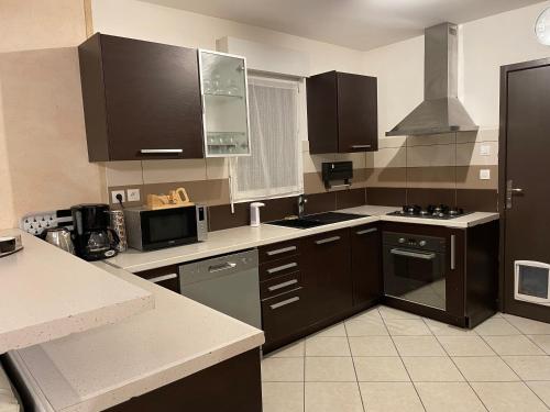 une cuisine avec des armoires marron et un four à plaques de cuisson dans l'établissement Maison entre mer et port, au Croisic