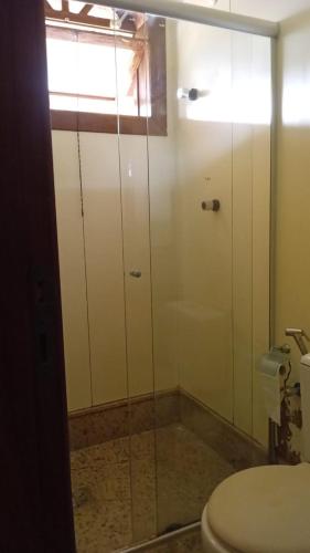 a bathroom with a toilet and a glass shower door at Castelo da Lagoa in Lagoa Santa