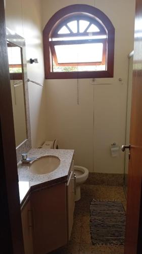 a bathroom with a sink and a toilet and a window at Castelo da Lagoa in Lagoa Santa