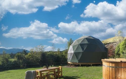 a large dome building in a field with a table at Hanmer Glamping in Hanmer Springs