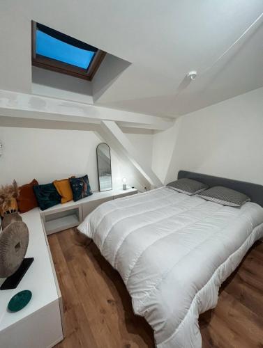 une chambre avec un grand lit blanc et une fenêtre dans l'établissement Au cœur des Chartrons, à Bordeaux