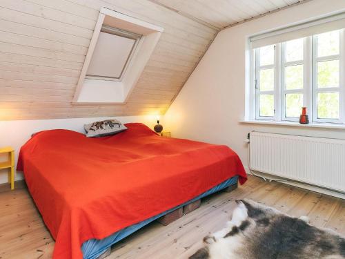 a bedroom with a red bed and two windows at Unique Coastal Retreat - By Traum Ferienwohnungen in Hadsund