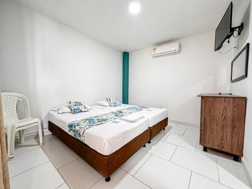 a bedroom with a bed and a wooden cabinet at Hotel Santiago de Tolú in Santiago