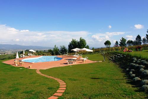a swimming pool with tables and chairs in a field at Agriturismo Bellavista in San Miniato