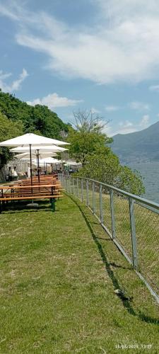 a fence with benches and an umbrella next to the water at Casa Caterina - Riva di Solto - Iseo Lake in Riva di Solto