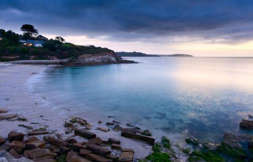 a beach with rocks in the water at sunset at Cabin by Beach & Nature Reserve Mon & Fri Check in Days Swanpool Falmouth Cornwall in Falmouth