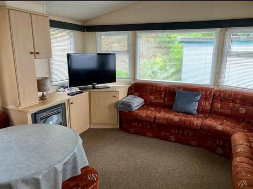 a living room with a couch and a flat screen tv at Cabin by Beach & Nature Reserve Mon & Fri Check in Days Swanpool Falmouth Cornwall in Falmouth