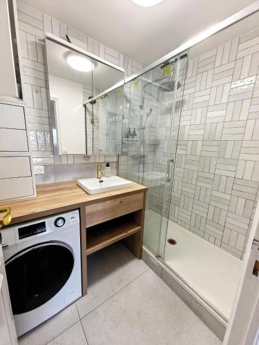 une salle de bain avec douche et lavabo et une machine à laver dans l'établissement Lux Belleville, à Paris
