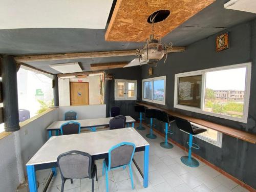 a dining room with a table and chairs and windows at Ndiamala in Darou Rhamane