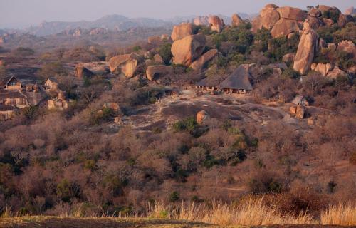a group of houses on a hill with rocks at Big Cave Camp in Matopos