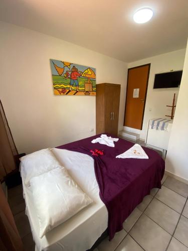a bedroom with a bed with a purple blanket at Pousada Porto de Amigos in Porto De Galinhas