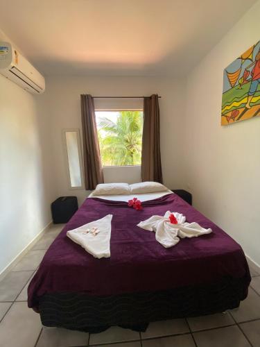 a bedroom with a purple bed with towels on it at Pousada Porto de Amigos in Porto De Galinhas