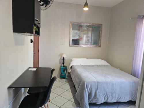 a bedroom with a bed and a table and a desk at Quarto Casal Aparecida-SP in Aparecida