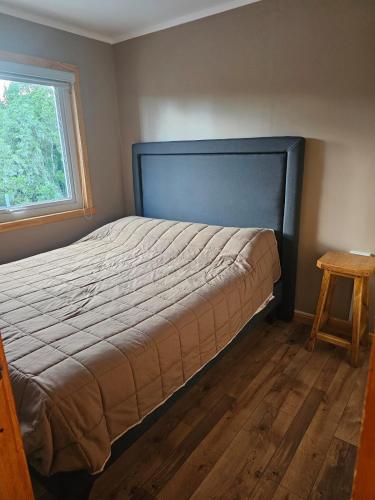 a bed in a bedroom with a window and a table at Casa Parcela, Bosques de Frutillar in Frutillar