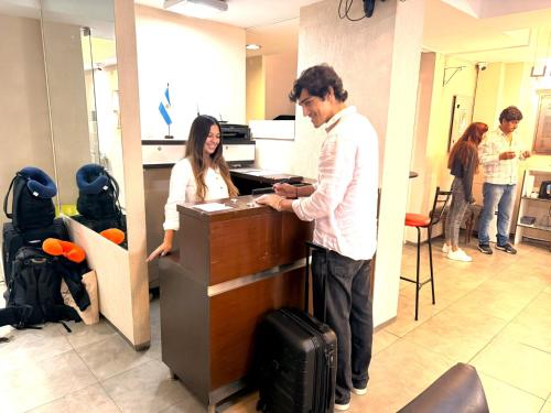 a man standing at a counter in an office with a woman at Edificio Recoleta - Hoteles Recoleta in Buenos Aires