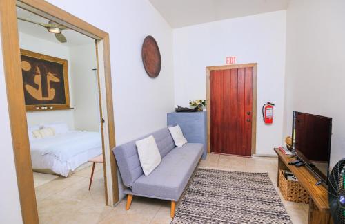 a living room with a couch and a bed and a television at Cozy Bed and Breakfast Studio Ladyville Airport BELIZE CITY in Ladyville