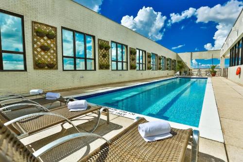 a swimming pool with chairs next to a building at Flat aconchegante in Brasilia