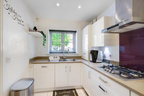 a kitchen with white cabinets and a sink at Meyers Close Modern 3 Bedrooms and 2 Bathrooms in Slough