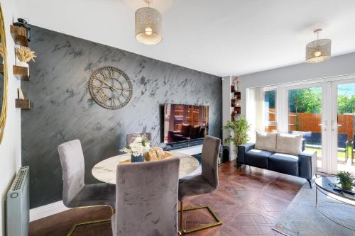 a living room with a table and chairs and a clock at Meyers Close Modern 3 Bedrooms and 2 Bathrooms in Slough