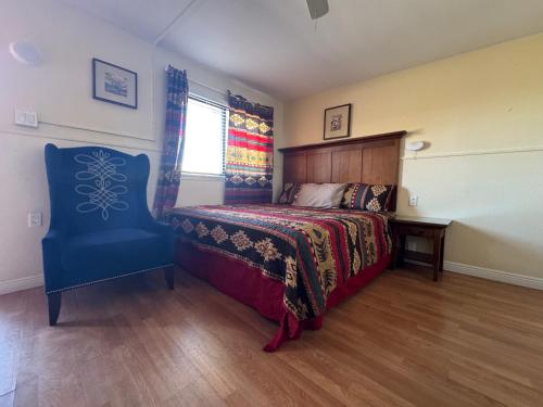 a bedroom with a bed and a blue chair at Apache Motel in Ruidoso