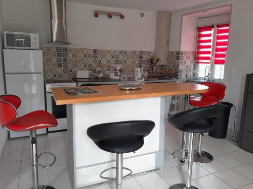 a kitchen with a counter with four stools at Sunlit Garden Escape Normandy in Isigny-sur-Mer