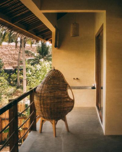 a rattan chair sitting on the porch of a house at Villa Jivanaya in Isda Islet