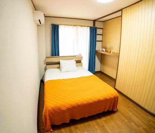 a bedroom with a yellow bed with a window at raikoエレベーター付き大人数向け一棟貸切宿 in Nishi-biwashima