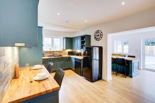 a kitchen with green cabinets and a wooden table at Brentwood Essex Work and Family Accommodation with 4 Ensuites and Secure Parking in Brentwood