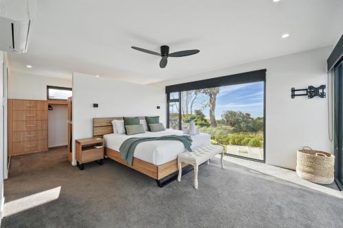 a bedroom with a bed and a large window at Beautiful Balook - 3 Bedroom Beach House in Lauderdale