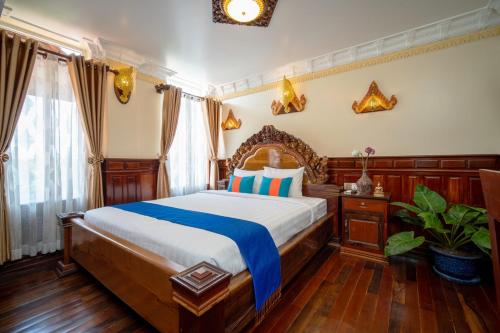 a bedroom with a large bed with a wooden headboard at Puok Resort in Phumĭ Puŏk Chăs