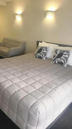 a white bed with pillows and a couch in a room at BK's Fountain Court Motel in Napier