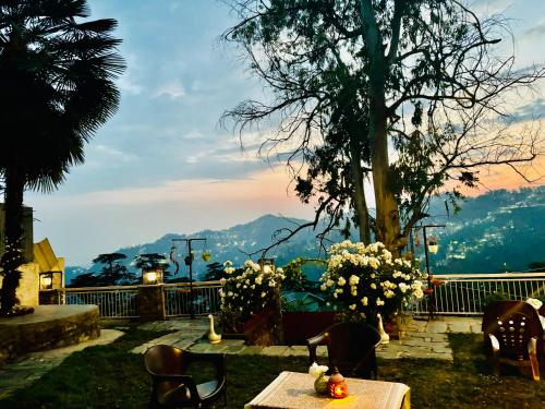 a table and chairs with a view of a mountain at Aaram Baagh Simla in Shimla